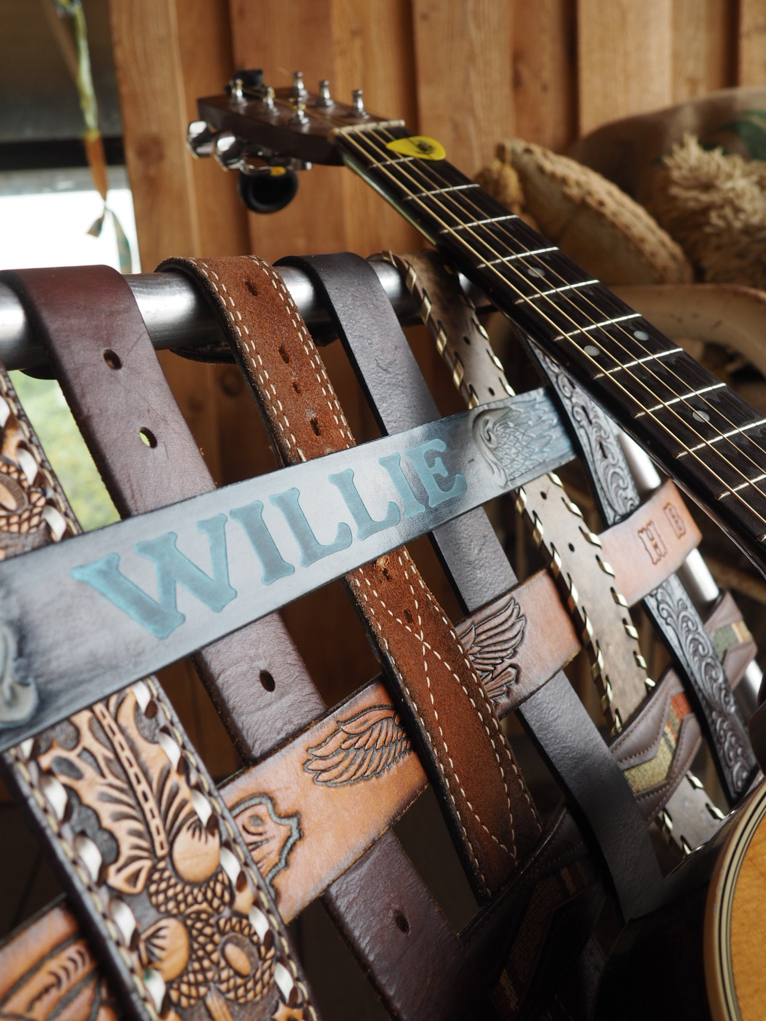 Close-up of a guitar with a detailed leather strap on a wooden surface
