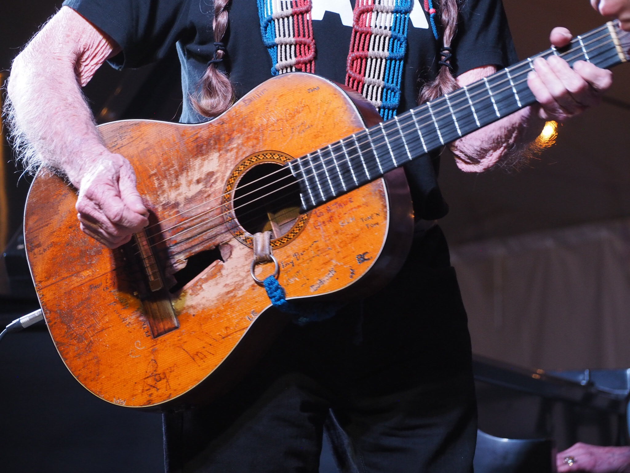 Willie Nelson playing a classical guitar with a blurred background