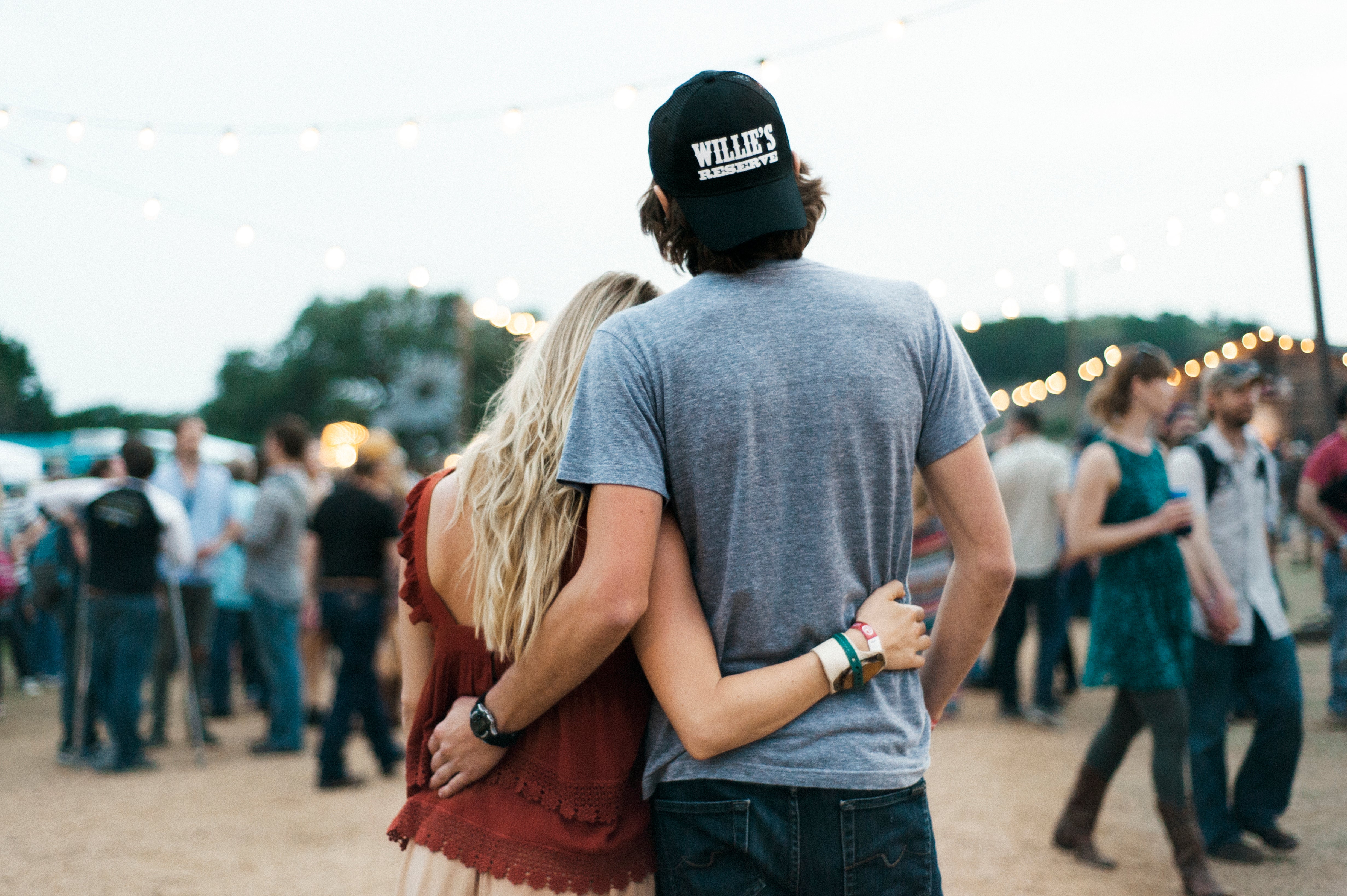 Two people embracing at a concert or festival with a crowd in the background.