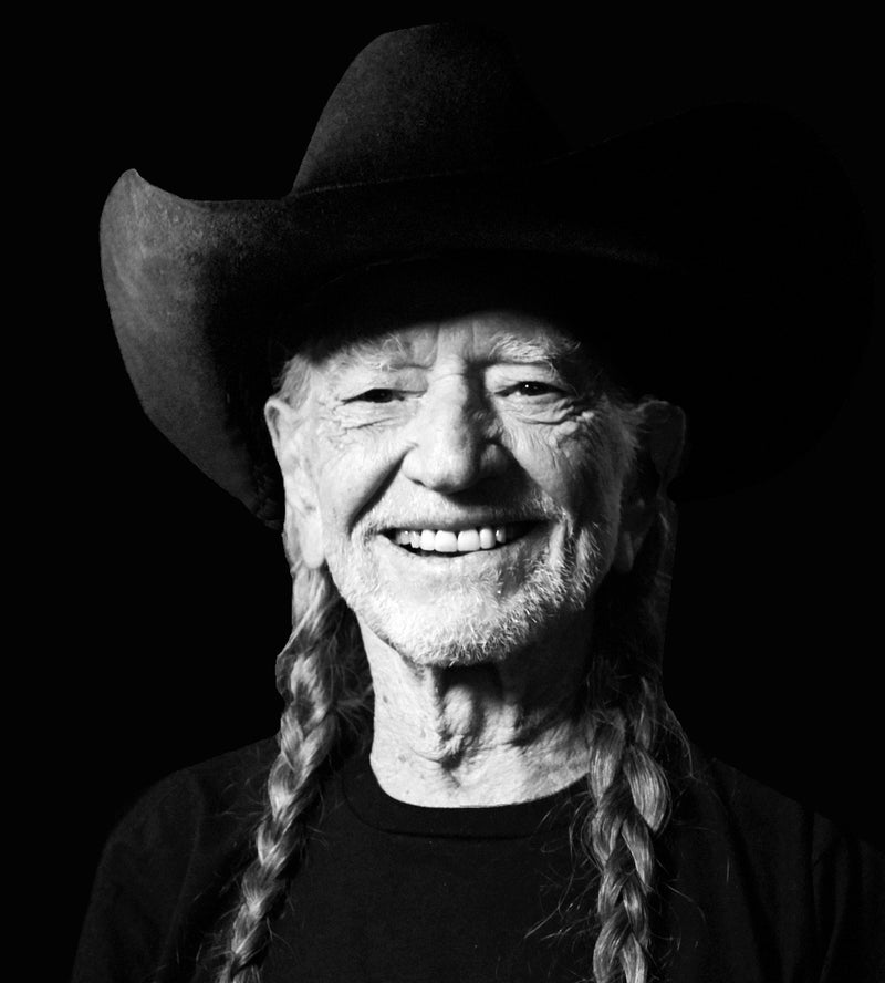 Black and white portrait of Willie Nelson wearing a cowboy hat with braided hair.