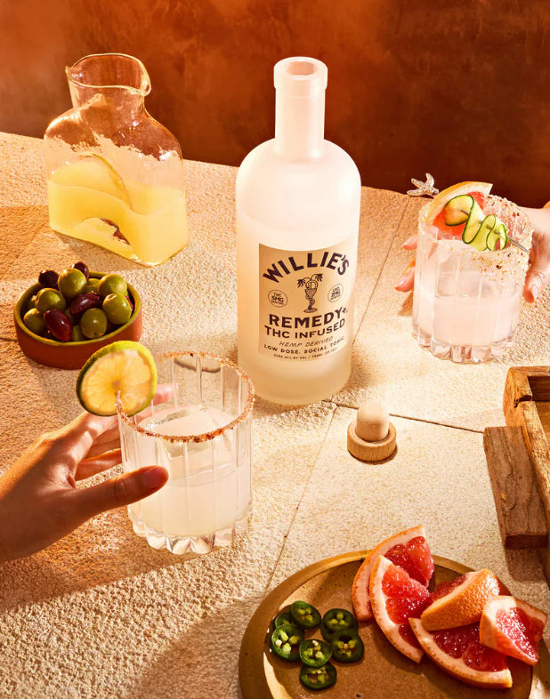 Willie's Remedy THC Infused bottle on a table with drinks and snacks