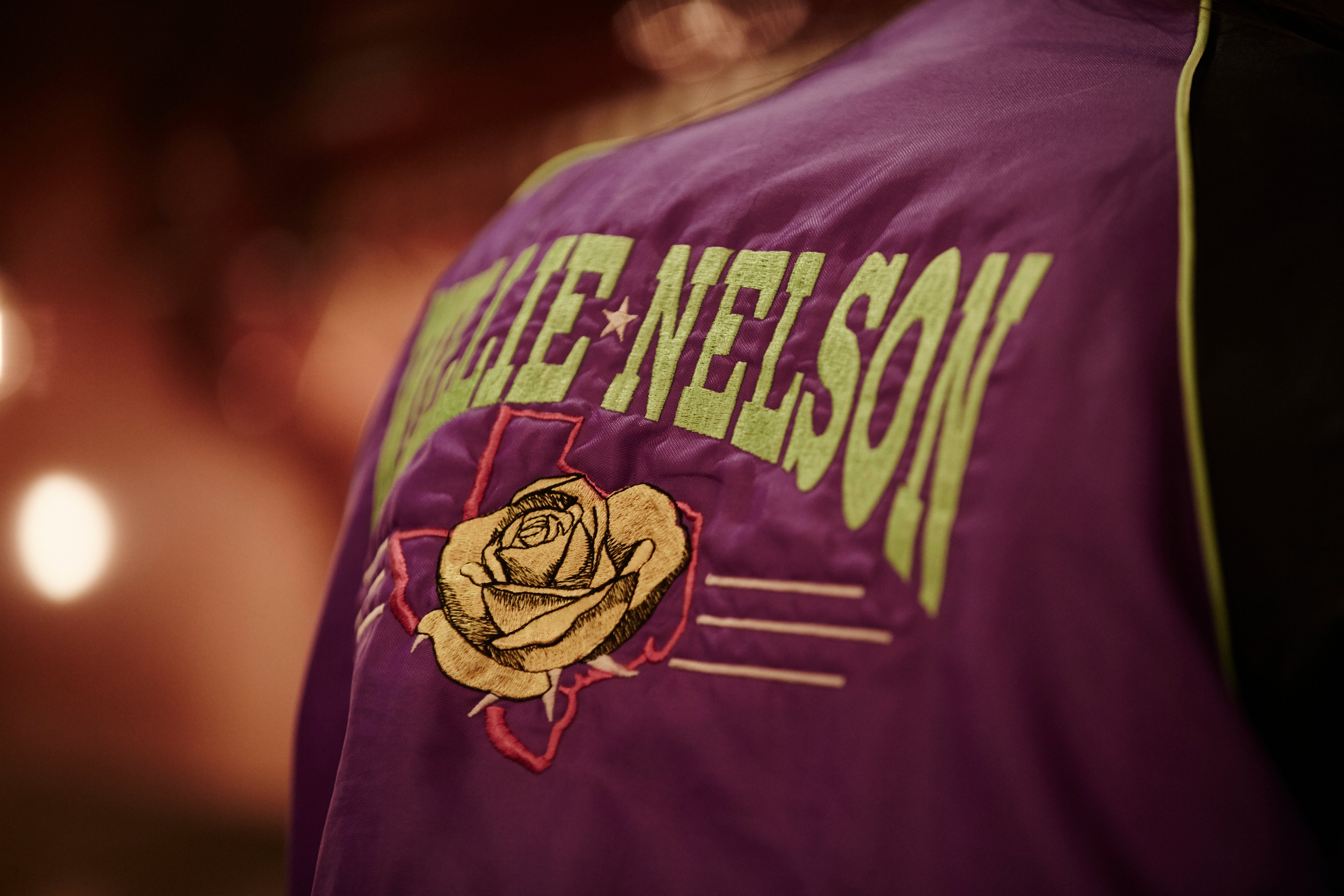 Purple jacket with 'Willie Nelson' and a rose design on a blurred background