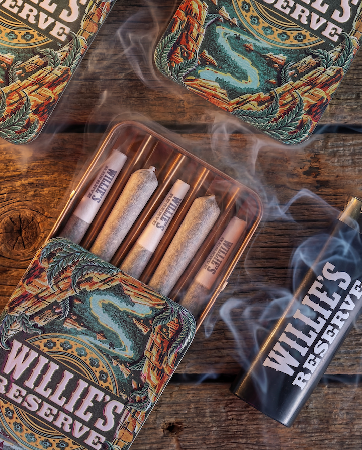 Willie's Reserve joints in a metallic tin with smoke on a wooden surface